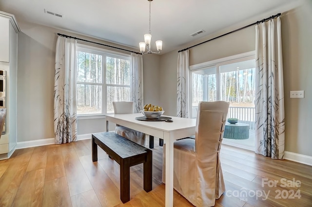 dining space with light hardwood / wood-style flooring and an inviting chandelier