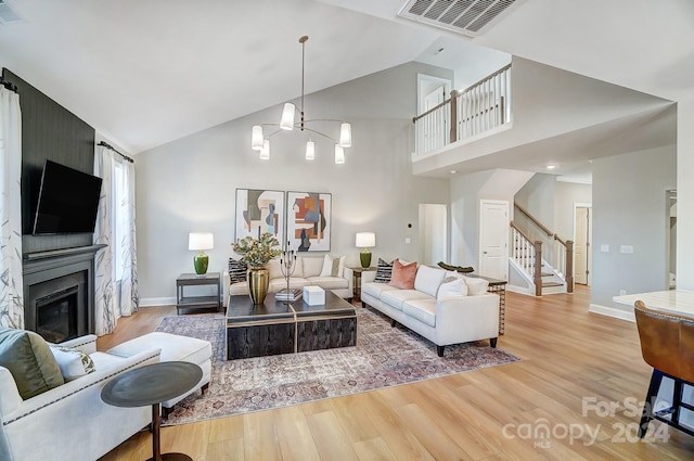 living room featuring high vaulted ceiling, light wood-type flooring, and a chandelier