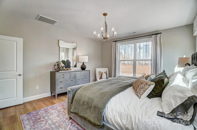 bedroom featuring an inviting chandelier and light hardwood / wood-style floors