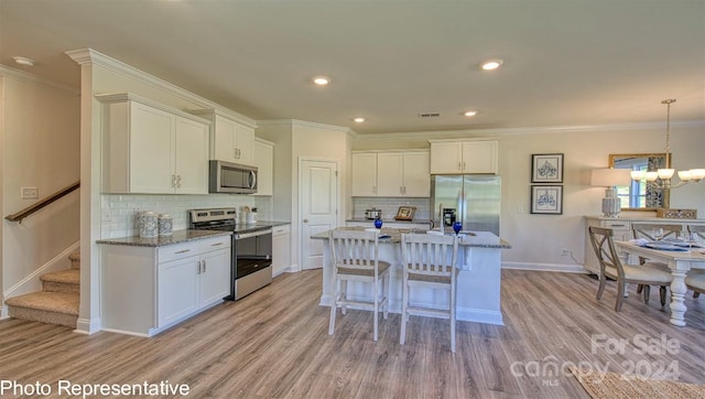 kitchen featuring light wood-type flooring, white cabinetry, backsplash, stainless steel appliances, and a breakfast bar area