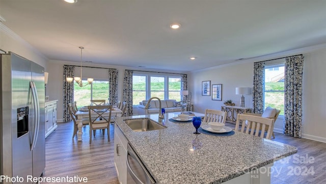 kitchen with stainless steel appliances, light hardwood / wood-style floors, a center island with sink, light stone counters, and sink