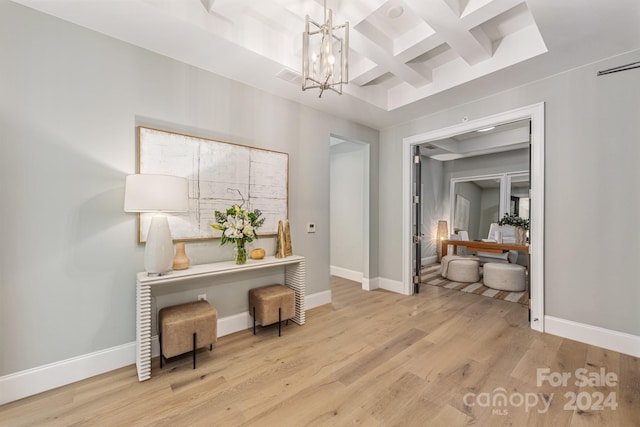 hallway with coffered ceiling, light hardwood / wood-style flooring, an inviting chandelier, and beamed ceiling