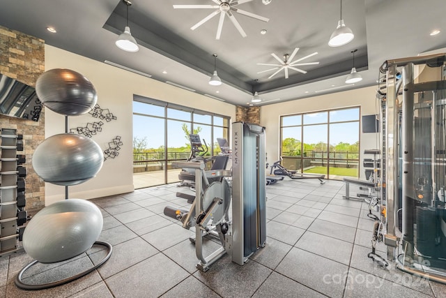 exercise room featuring a raised ceiling and ceiling fan