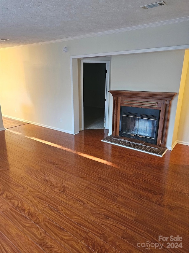 unfurnished living room featuring a textured ceiling, dark hardwood / wood-style flooring, and a tiled fireplace