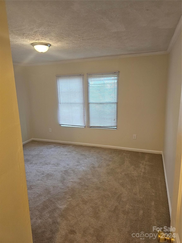 unfurnished room featuring a textured ceiling, dark carpet, and ornamental molding