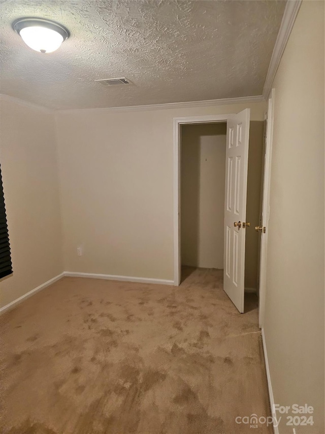 carpeted empty room with a textured ceiling and ornamental molding