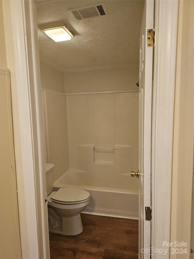 bathroom featuring tub / shower combination, hardwood / wood-style flooring, toilet, and a textured ceiling