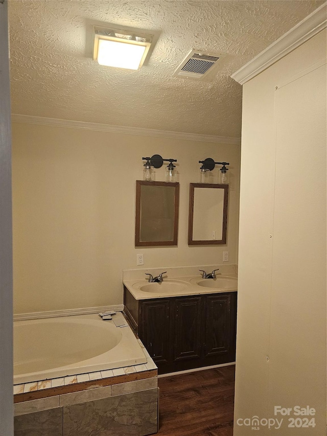 bathroom featuring a textured ceiling, hardwood / wood-style flooring, double vanity, and ornamental molding