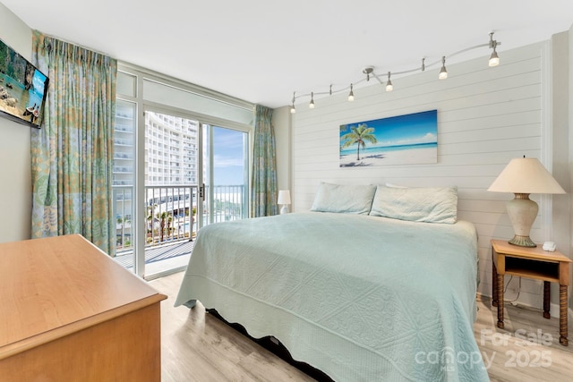 bedroom with rail lighting, access to outside, and light hardwood / wood-style flooring