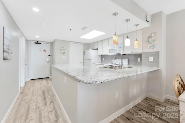 kitchen with white cabinetry, white appliances, kitchen peninsula, and hanging light fixtures