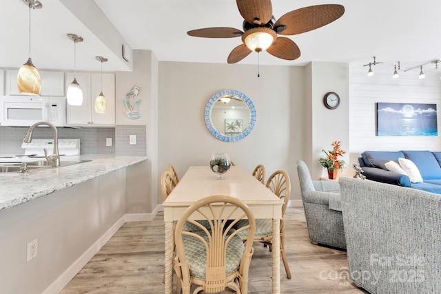 dining room with ceiling fan, sink, and light hardwood / wood-style floors