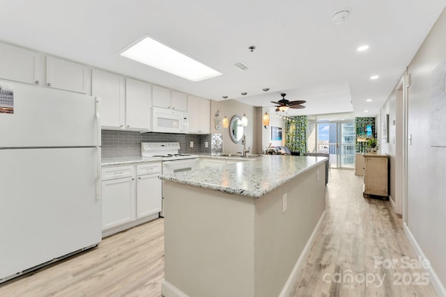 kitchen featuring tasteful backsplash, light wood-type flooring, white appliances, light stone countertops, and white cabinets