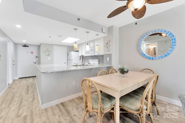 dining area with ceiling fan, sink, and light hardwood / wood-style flooring