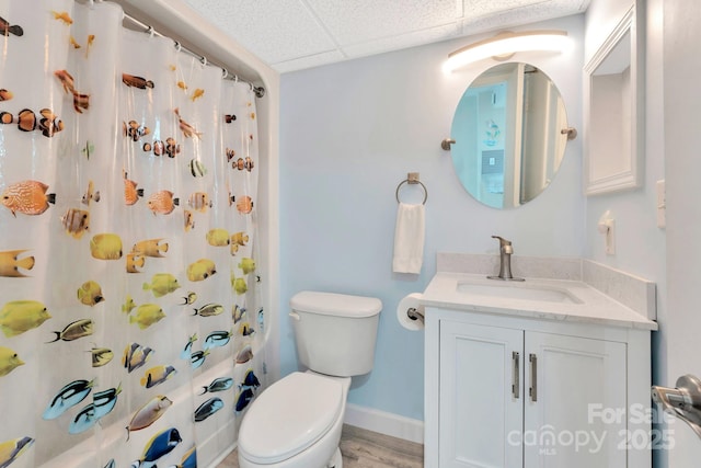 bathroom with hardwood / wood-style flooring, vanity, toilet, and a drop ceiling