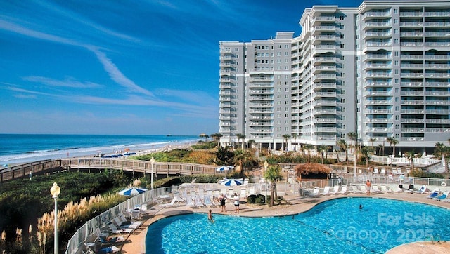 view of pool featuring a water view and a view of the beach