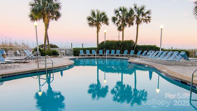 pool at dusk with a patio area