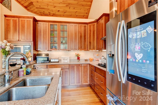 kitchen with lofted ceiling, stainless steel refrigerator with ice dispenser, sink, wood ceiling, and light stone counters