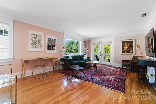 living room with french doors, crown molding, and light wood-type flooring