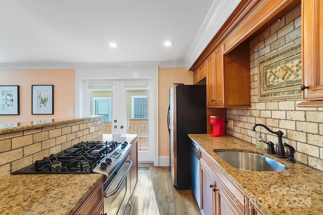 kitchen featuring tasteful backsplash, appliances with stainless steel finishes, light stone counters, and light wood-type flooring