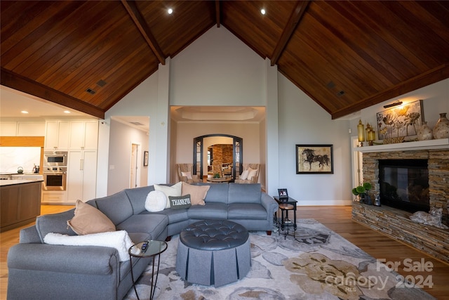 living room with wood ceiling, light hardwood / wood-style floors, high vaulted ceiling, a fireplace, and beamed ceiling