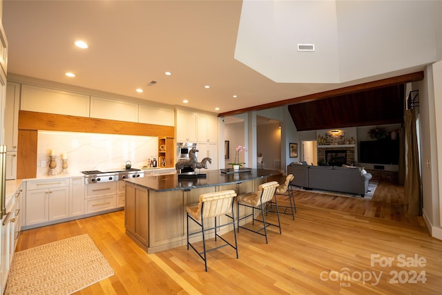 kitchen featuring light wood-type flooring, white cabinetry, a kitchen bar, and a center island