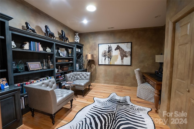 living area featuring ornamental molding and light hardwood / wood-style flooring