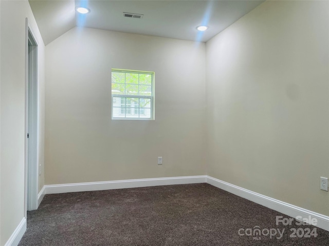 carpeted spare room featuring vaulted ceiling