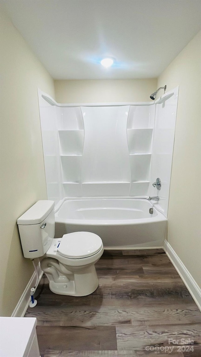 bathroom with hardwood / wood-style floors, washtub / shower combination, and toilet