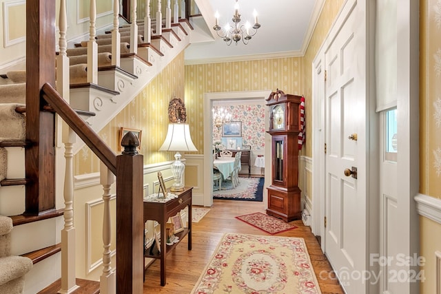 foyer featuring ornamental molding, hardwood / wood-style flooring, and a chandelier