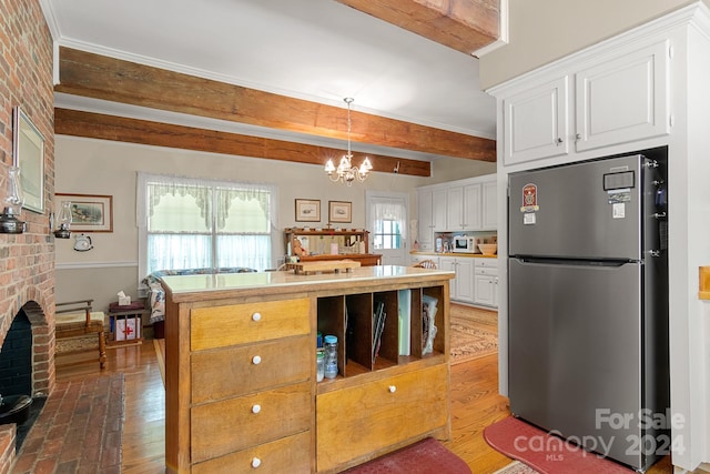 kitchen with white cabinetry, dark wood-type flooring, a brick fireplace, beam ceiling, and stainless steel refrigerator