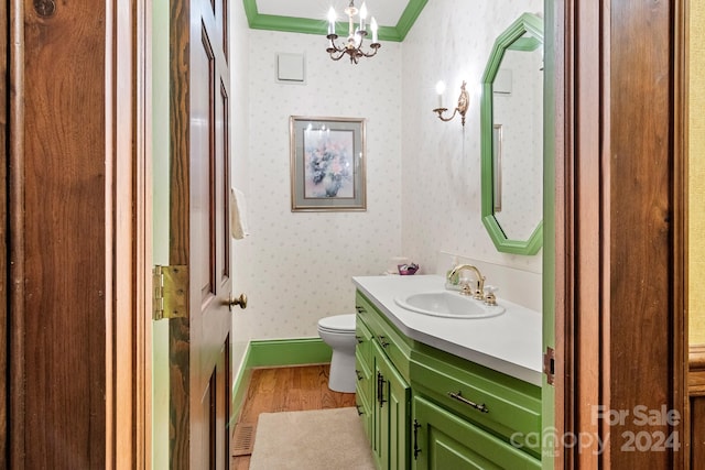 bathroom featuring crown molding, wood-type flooring, a notable chandelier, toilet, and large vanity