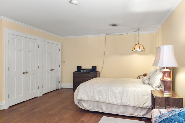 bedroom with crown molding, two closets, and dark hardwood / wood-style floors