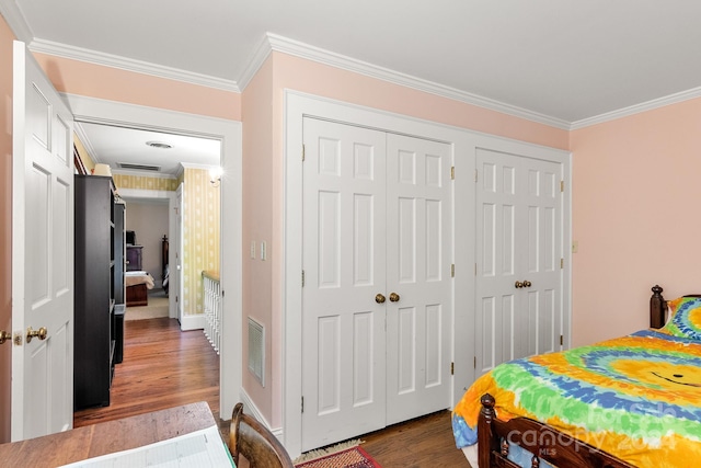 bedroom with two closets, dark wood-type flooring, and ornamental molding