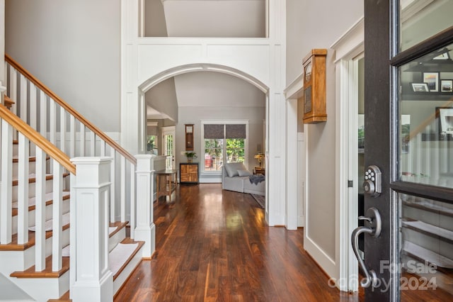 entryway featuring dark wood-type flooring and a towering ceiling