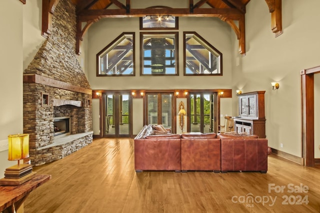 living room featuring french doors, high vaulted ceiling, light wood-type flooring, and a fireplace