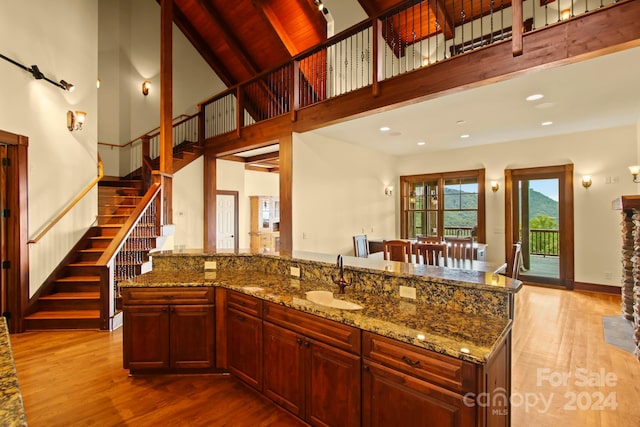 kitchen featuring sink, a kitchen island, wood ceiling, high vaulted ceiling, and light hardwood / wood-style flooring