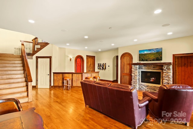 living room featuring a stone fireplace and light hardwood / wood-style flooring