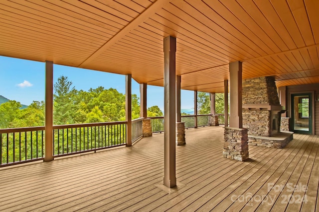 wooden terrace featuring an outdoor stone fireplace