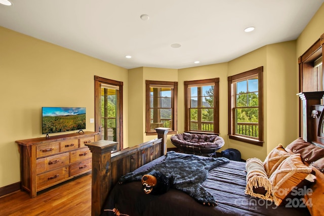 bedroom with access to outside, multiple windows, and hardwood / wood-style floors