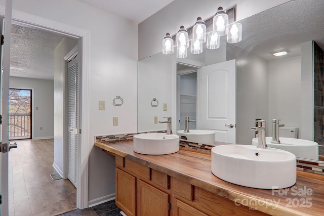 bathroom featuring double vanity, a textured ceiling, and a sink