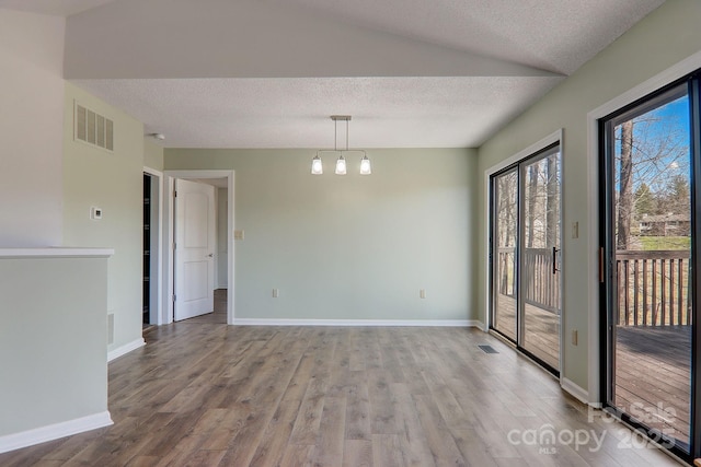 spare room featuring baseboards, a textured ceiling, visible vents, and wood finished floors