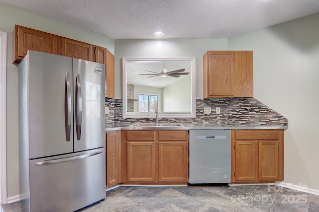 kitchen featuring appliances with stainless steel finishes, a sink, light countertops, a textured ceiling, and backsplash