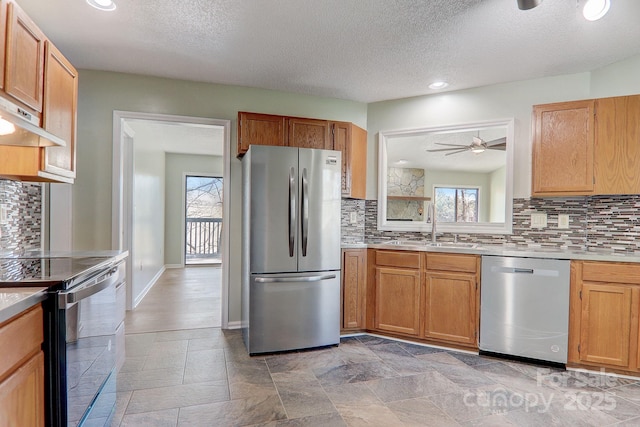 kitchen featuring baseboards, appliances with stainless steel finishes, light countertops, and a sink