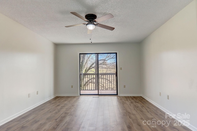 unfurnished room with a textured ceiling, wood finished floors, a ceiling fan, and baseboards