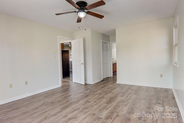 unfurnished room with baseboards, a textured ceiling, a ceiling fan, and light wood-style floors