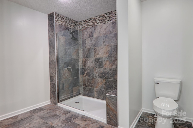 bathroom with toilet, a textured ceiling, baseboards, and tiled shower