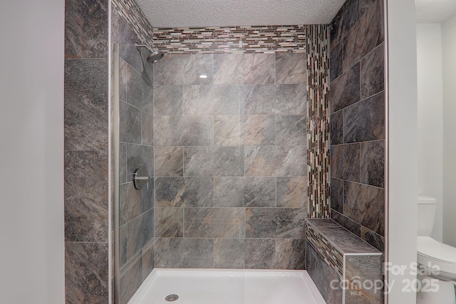 full bathroom featuring a stall shower, a textured ceiling, and toilet