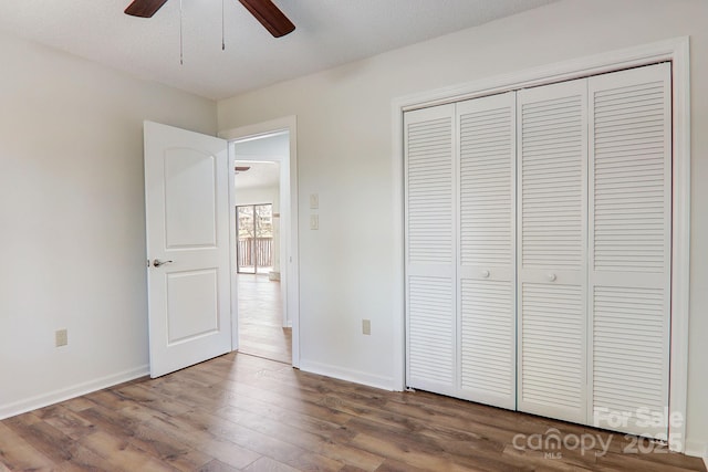 unfurnished bedroom with ceiling fan, a closet, baseboards, and wood finished floors