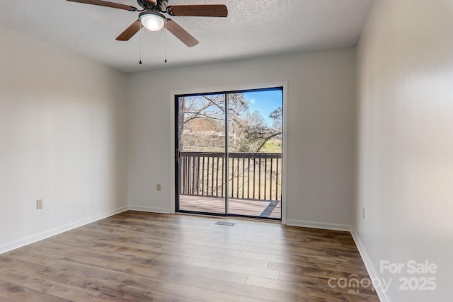 empty room with visible vents, ceiling fan, a textured ceiling, wood finished floors, and baseboards