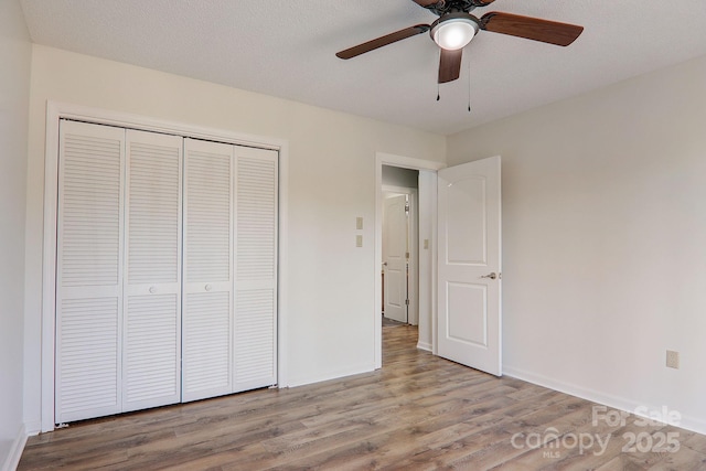 unfurnished bedroom with ceiling fan, a textured ceiling, wood finished floors, baseboards, and a closet